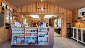 Un interior rústico con paredes de madera, un mostrador central que exhibe aperitivos y un ventilador de techo.