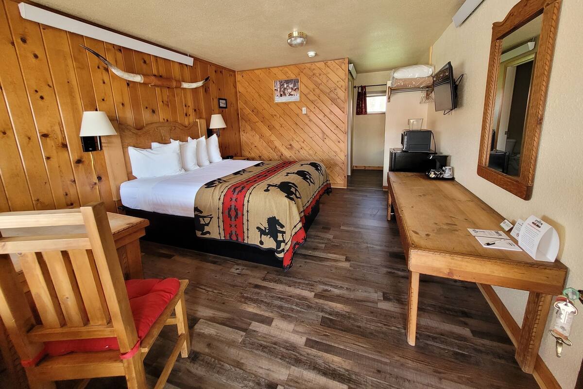 A wooden-paneled room with a bed, a desk, and a chair.
