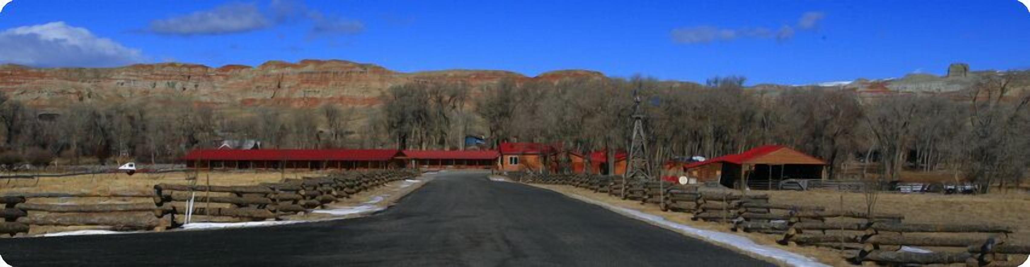 A rural road with a series of red-roofed buildings and a large open field.