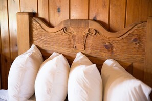 A wooden headboard with a carved bull's head design, flanked by four white pillows.