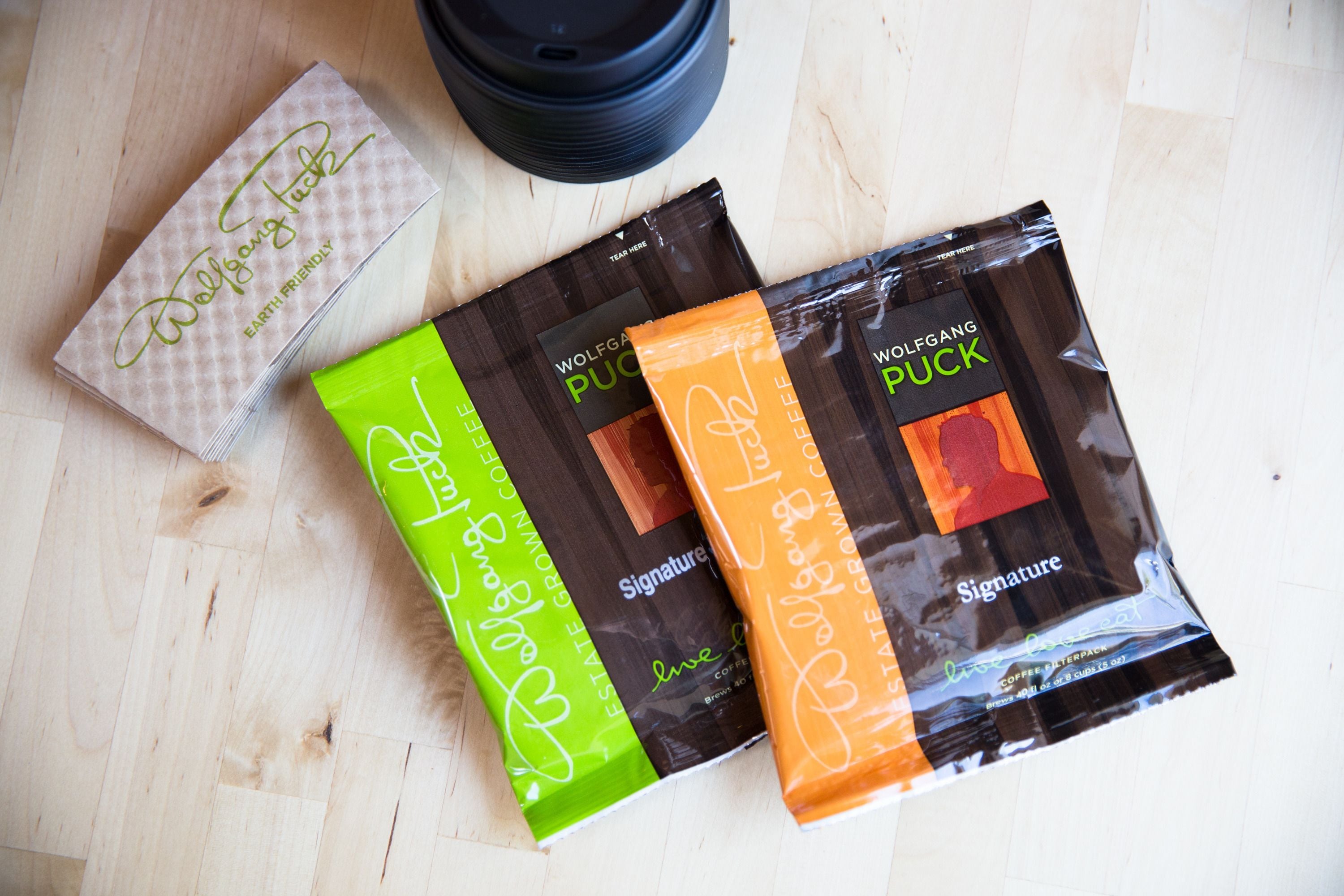 Two coffee bags and a coffee cup on a wooden surface.