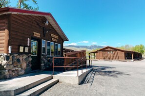 A rustic wooden building with a stone foundation, labeled as an office and general store, with a clear view of the surrounding landscape.