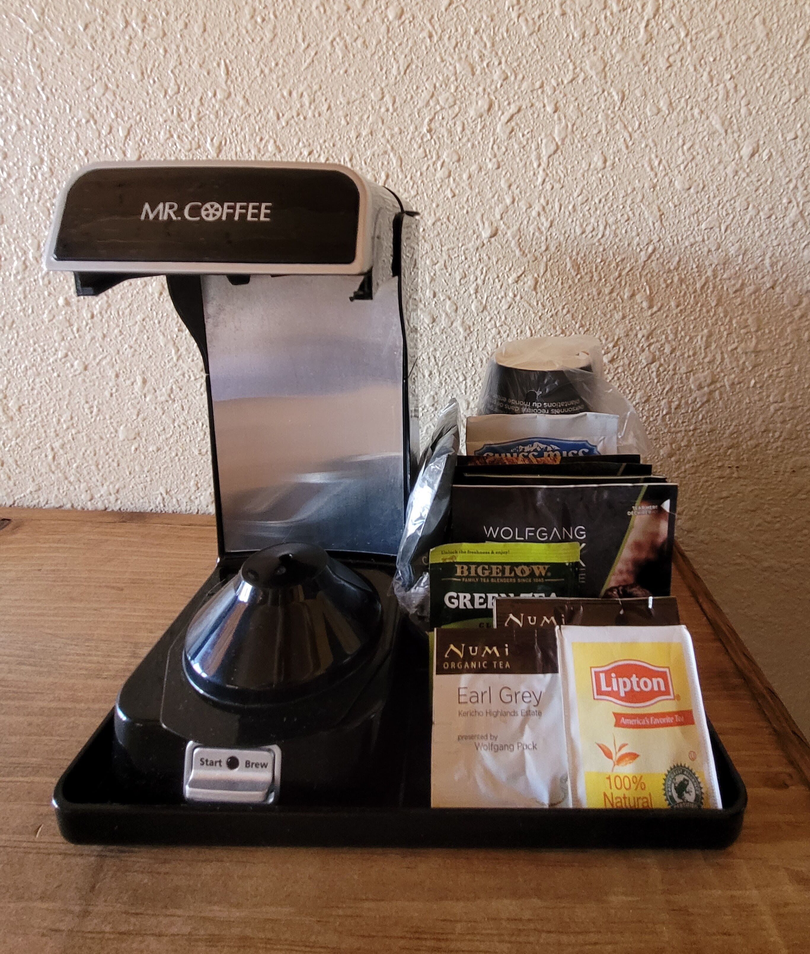 Une machine à café avec un présentoir de sachets de thé et de capsules de café.