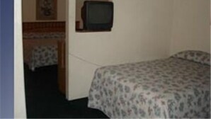A small, single-bed room with a television mounted on the wall. - Colonade Motel (Mesa)