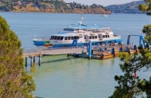 A ferry docked at a pier with a clear view of the water and distant hills. - Hotel Sausalito (Sausalito)