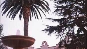 Una fuente frente a un edificio con una torre de reloj.