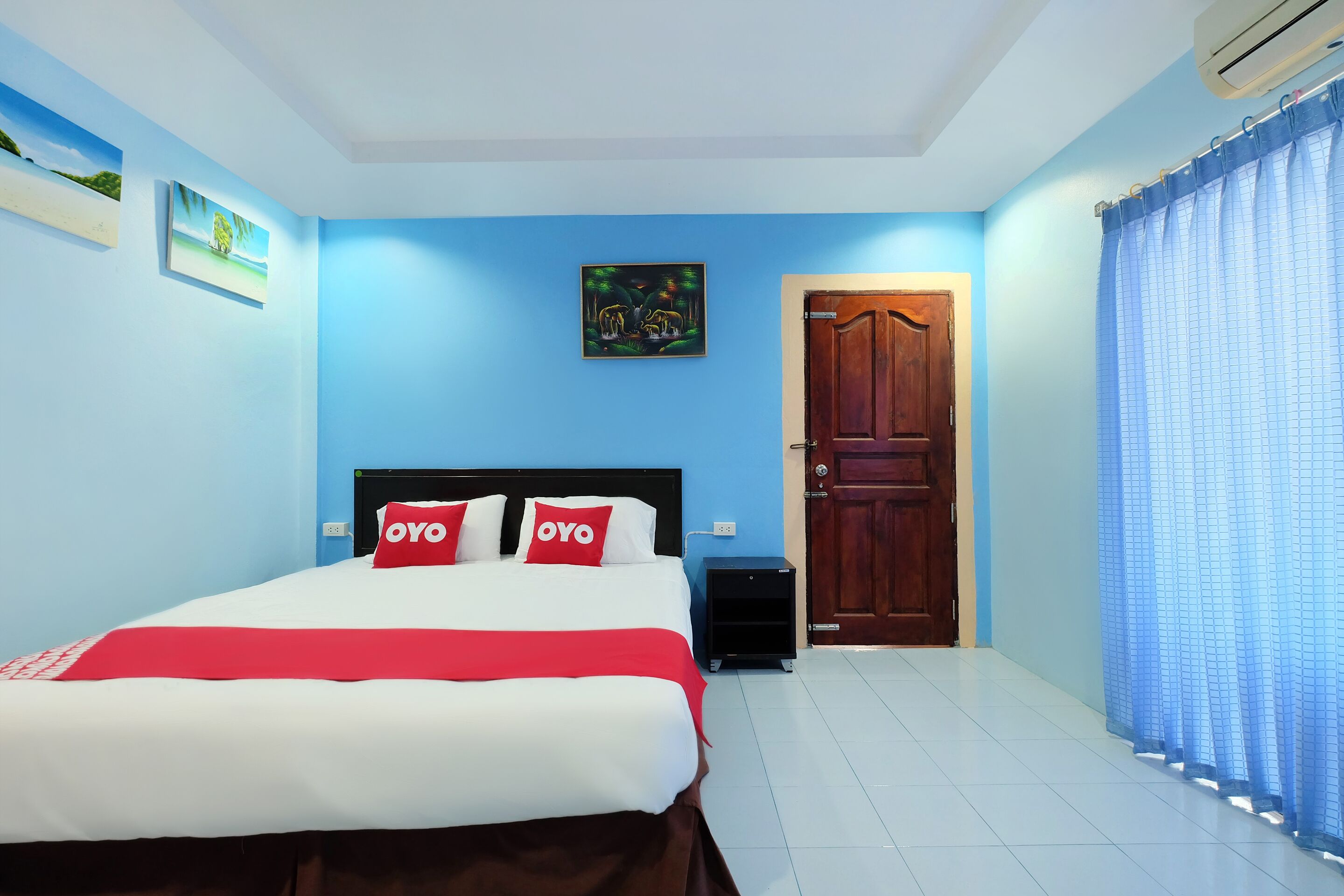 A bedroom with a bed, a nightstand, a door, and a window with curtains.