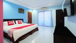 Habitación de hotel con cama, televisor de pantalla plana, un cuadro en la pared y ventana con cortinas.