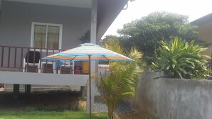 A pool area with a colorful striped umbrella, a small palm tree, and a concrete wall. - Lanta Dream Garden Pool Villa (Ko Lanta)