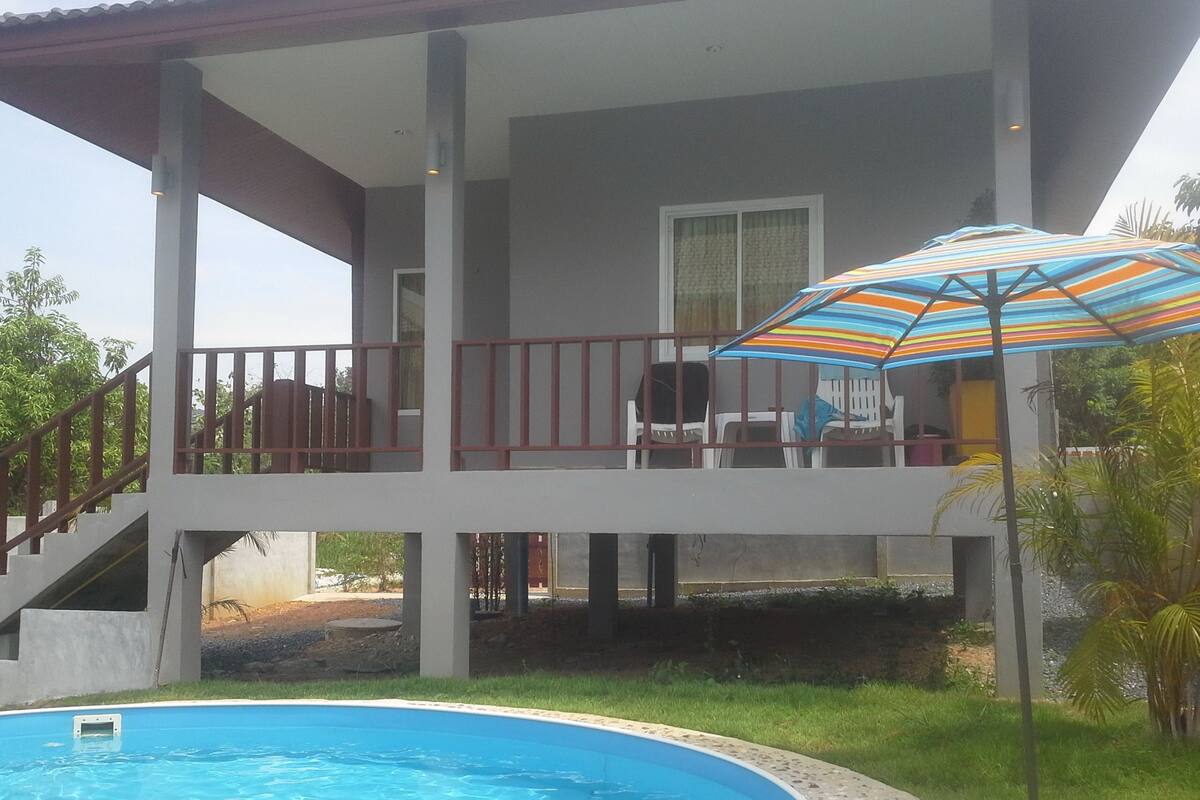 A two-story building with a balcony, a pool, and outdoor seating.