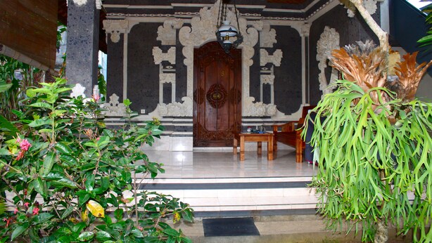 An ornate entrance with a wooden door, a tiled floor, and a bench. - Swan Inn (Ubud)