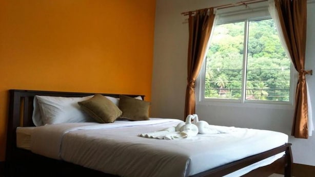 A neatly made bed with white linens and a swan-shaped towel arrangement. - Lanta Sun Smile Place (Ko Lanta)