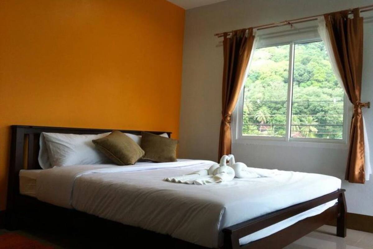A neatly made bed with white linens and a swan-shaped towel arrangement.