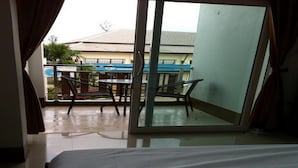A hotel room with a bed, a sliding glass door leading to an outdoor area with a table and chairs. - Lanta Sun Smile Place (Ko Lanta)