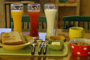 A breakfast tray with toast, a bowl of cereal, and three glasses of juice.