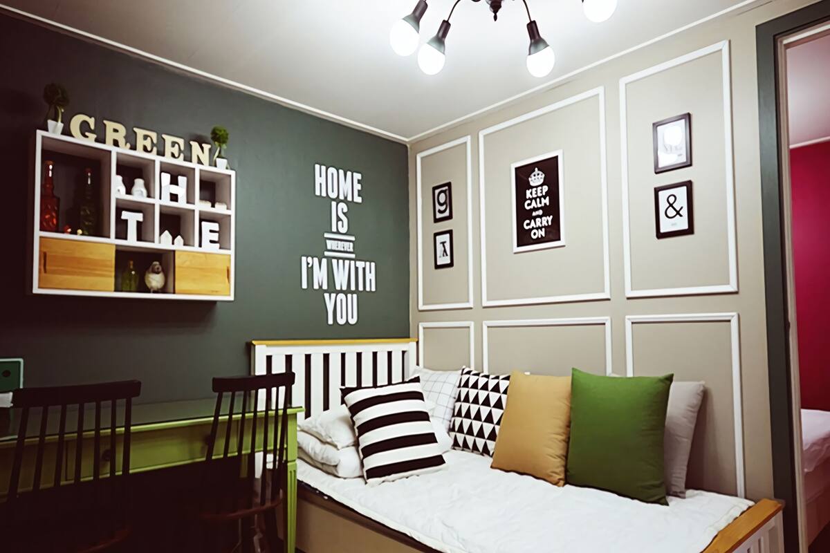 A bedroom with a bed, a desk, and a shelving unit.