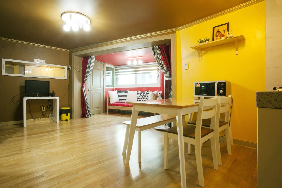 A compact living space with a dining area, kitchenette, and a red accent wall.