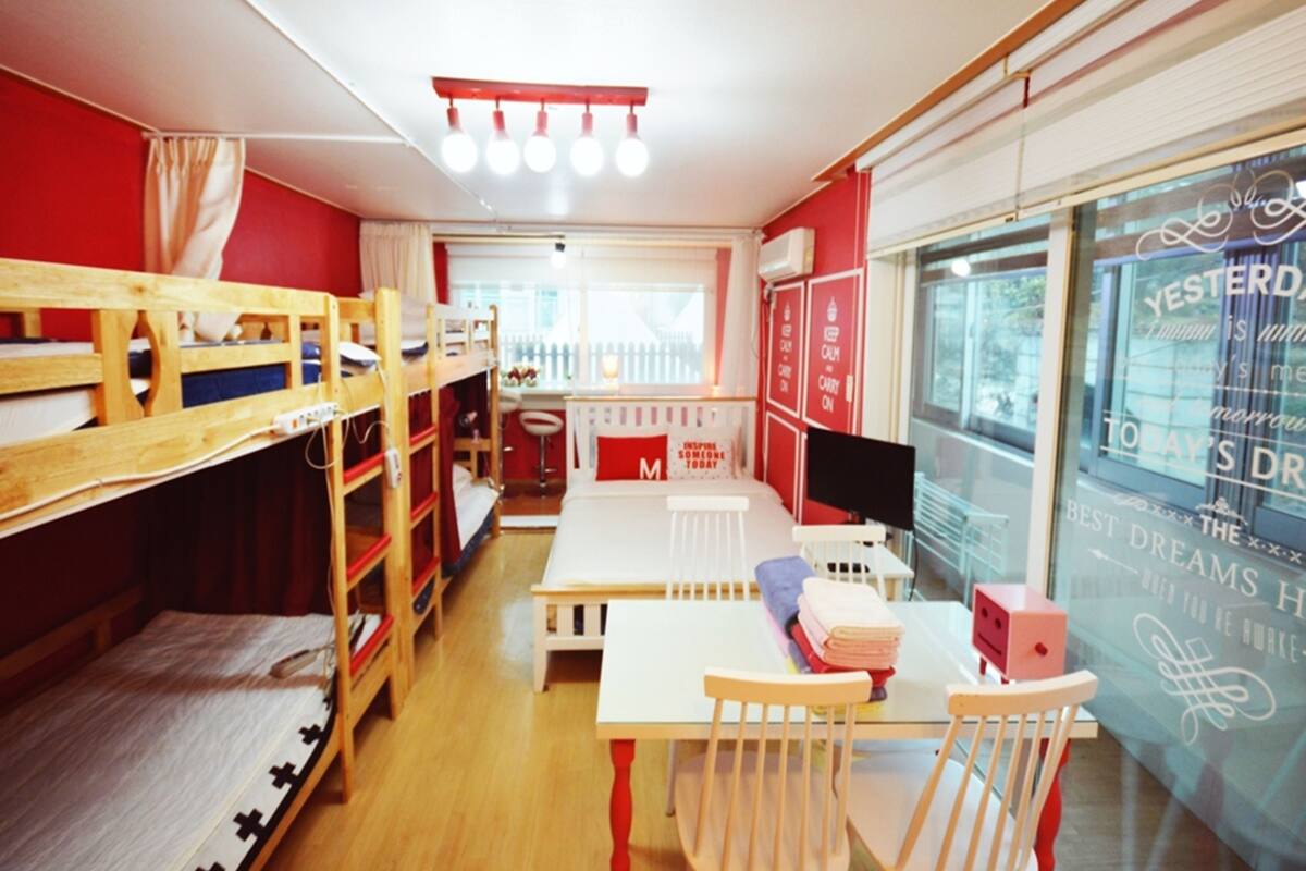 A room with bunk beds, a desk, and a chair. There is a window with motivational quotes and a view of the outside.
