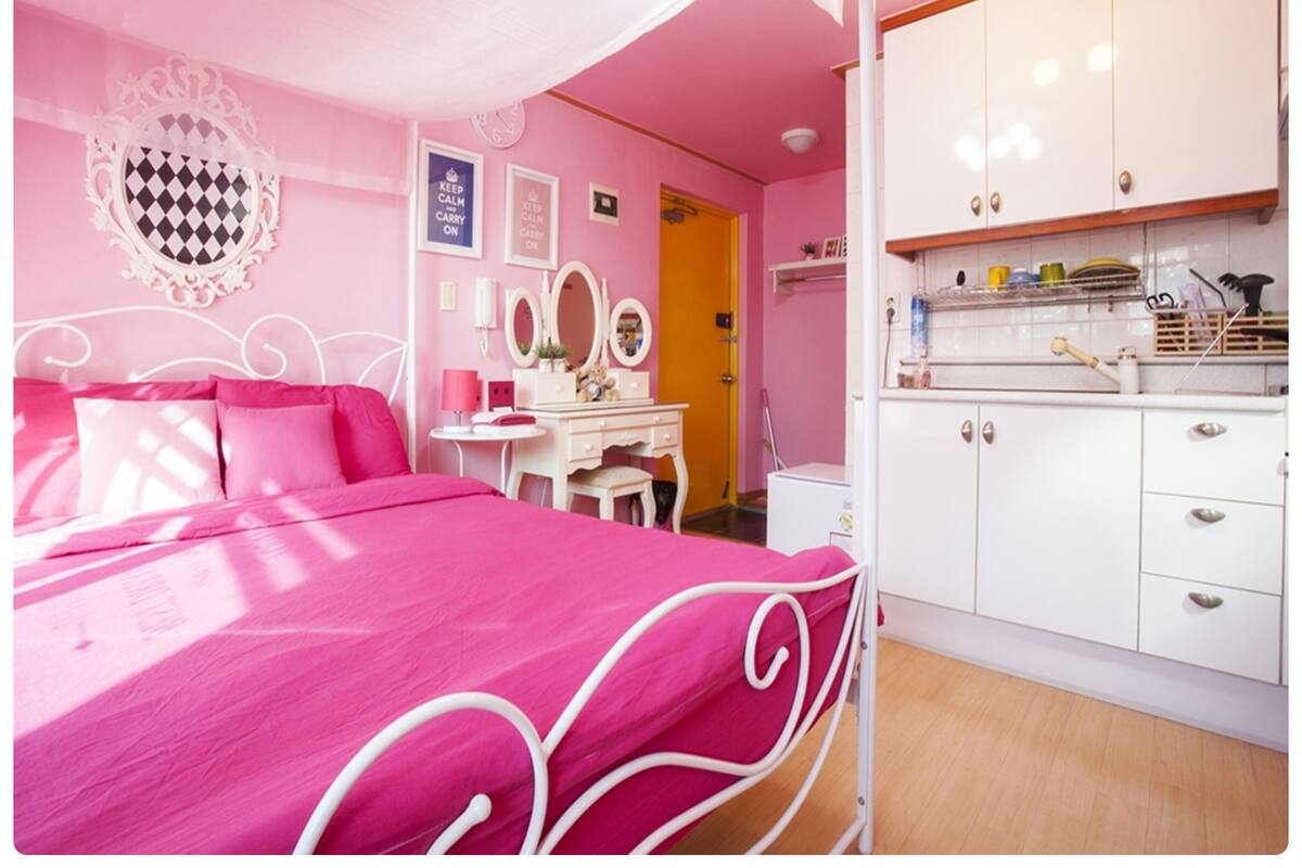 A pink-themed bedroom with a bed, dresser, and vanity.