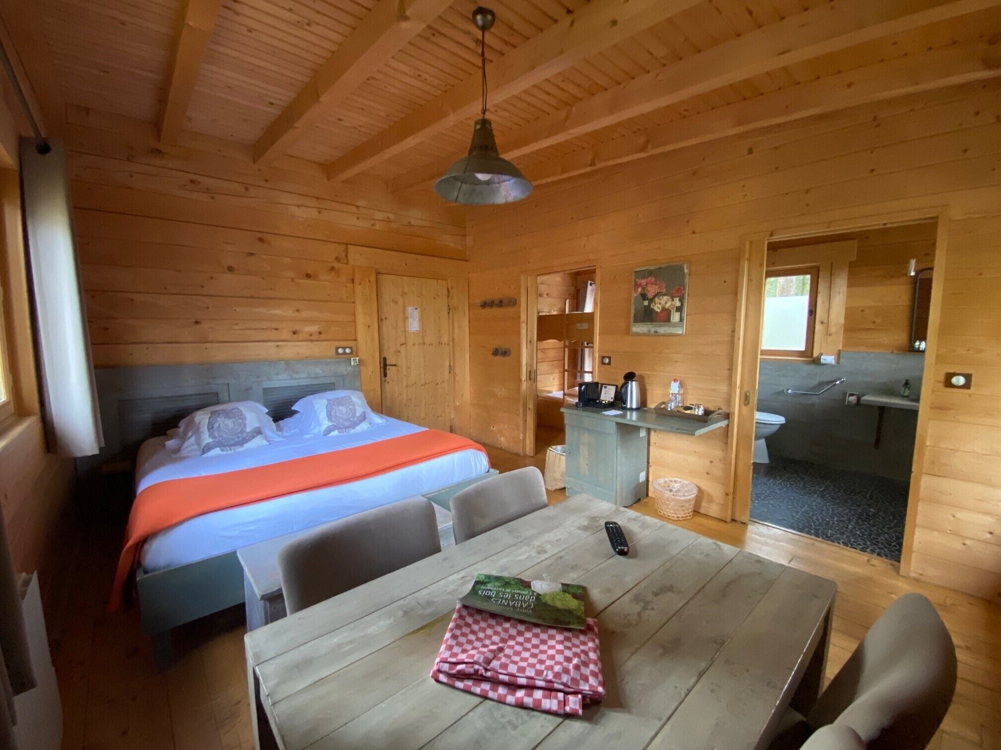 Een houten kamer met een bed, een tafel en een kitchenette.