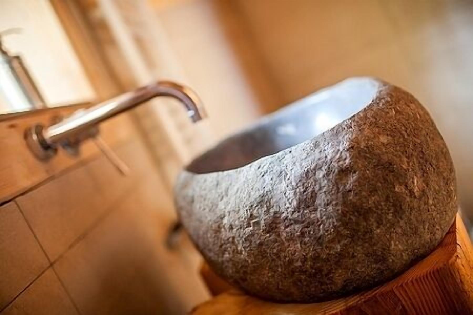 A stone sink with a curved faucet in a bathroom.