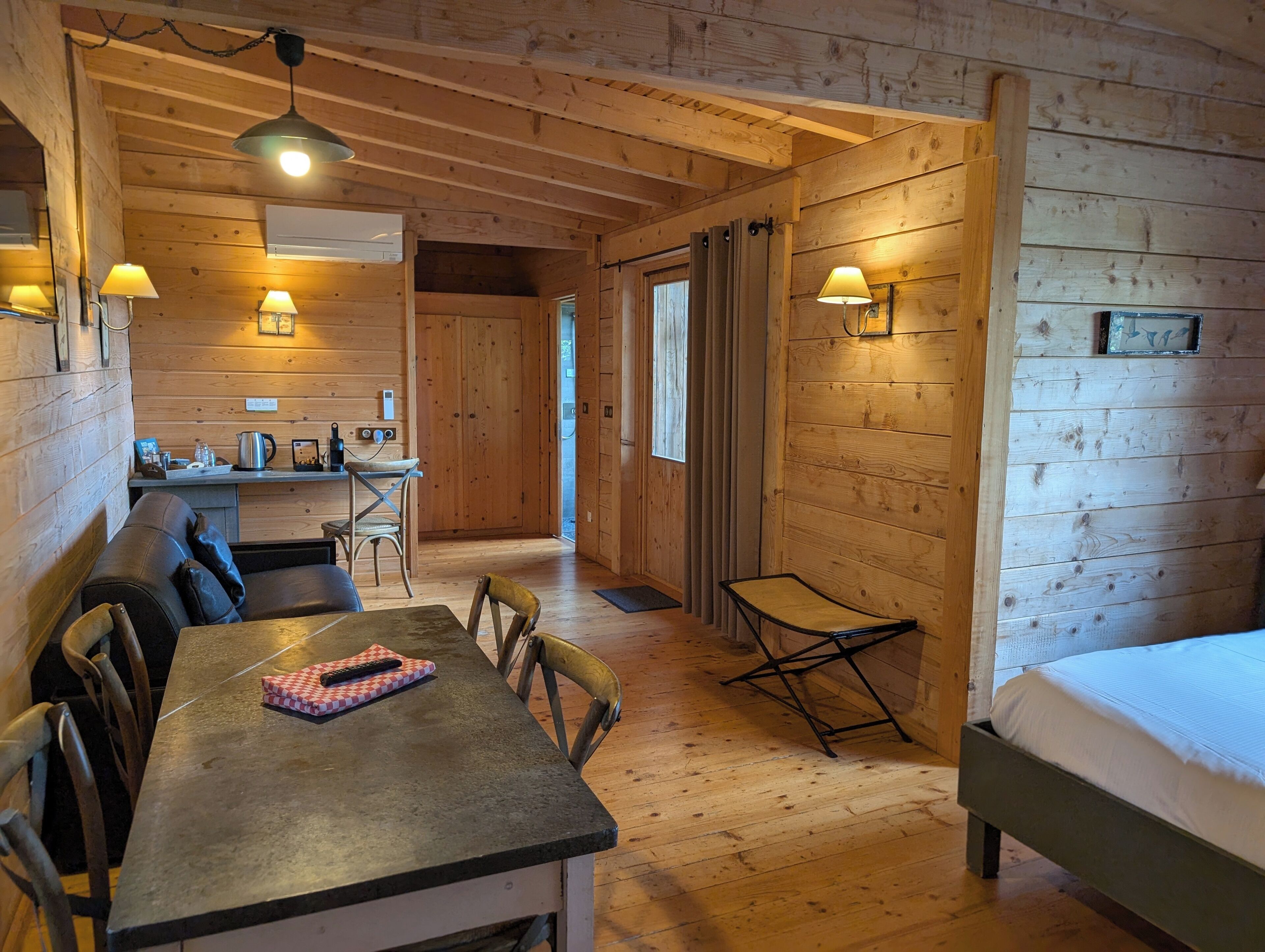A cozy cabin interior with a dining area, a kitchen, and a bedroom.