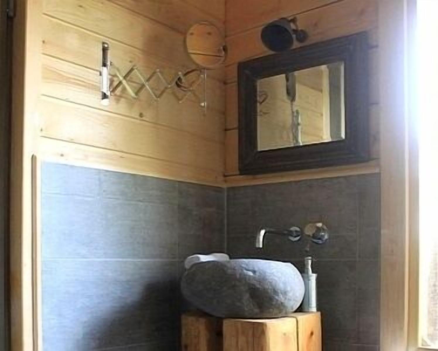 Une salle de bain avec un meuble-lavabo en bois, un lavabo en pierre et un miroir au-dessus du lavabo.