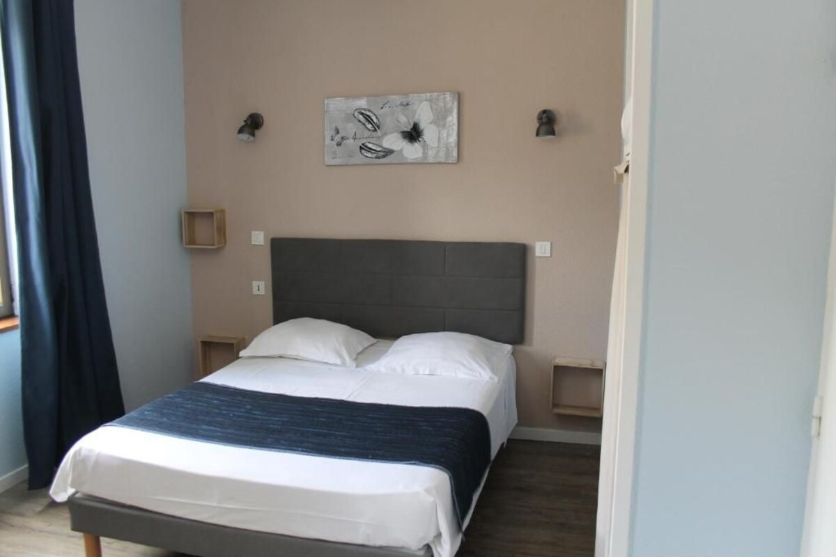 Een slaapkamer met een bed, hoofdbord, een wanddecoratie en nachtkastjes.