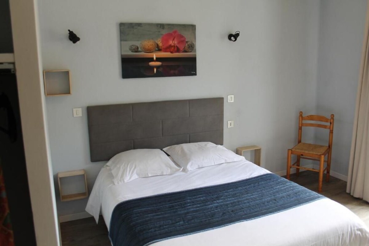 Une chambre à coucher avec un lit, une chaise, un tableau et une petite table.