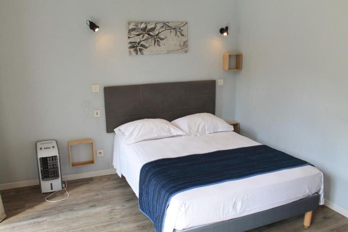 A bedroom with a bed, bedside tables, a heater, and a wall-mounted artwork.