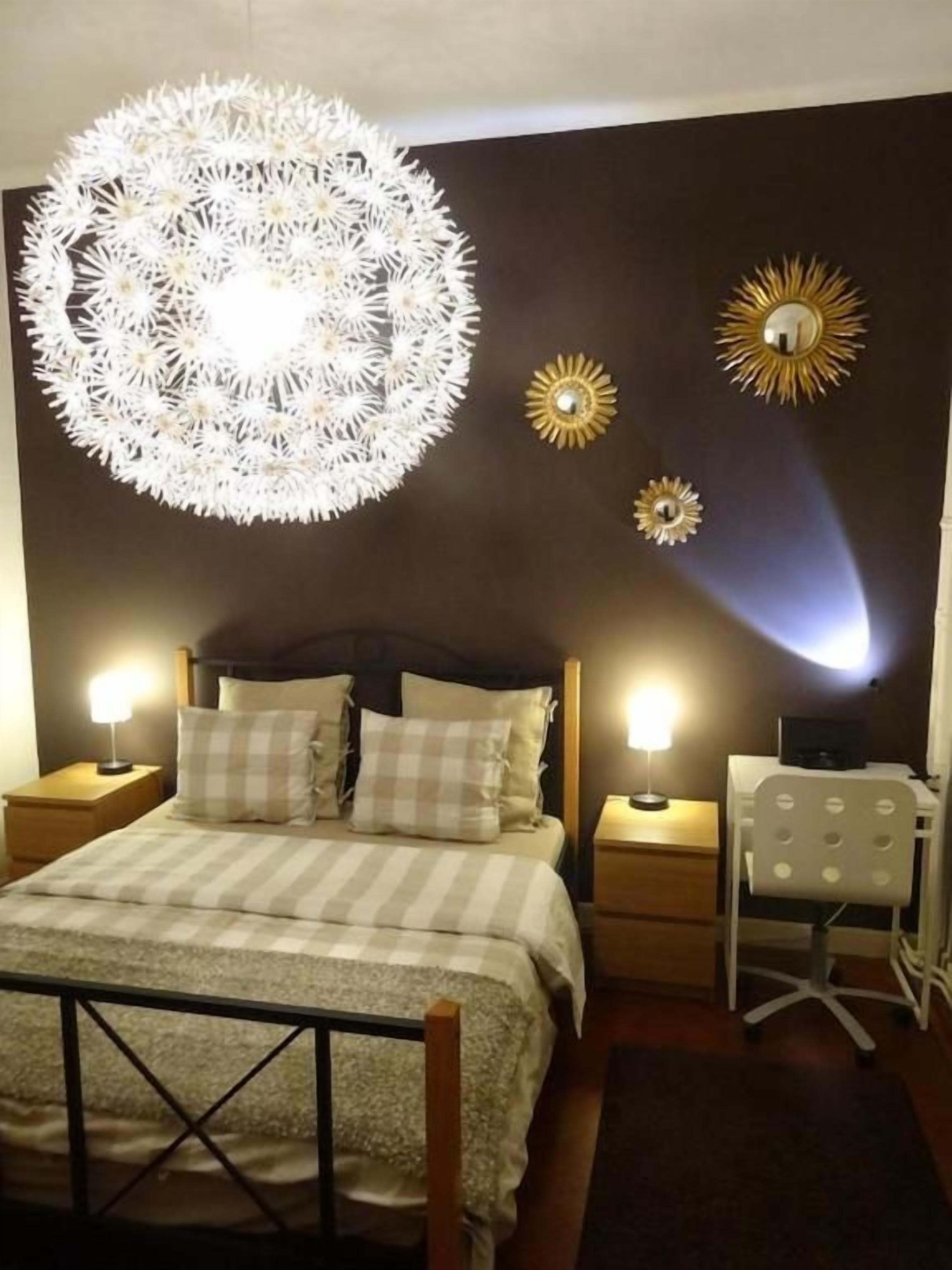 Un dormitorio con cama, mesitas de noche, un escritorio y decoración en la pared.
