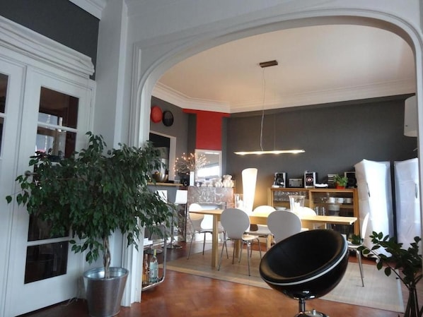 A modern interior with a dining area, a black chair, and a potted plant. - Welcome to my place B&B (Brussels)