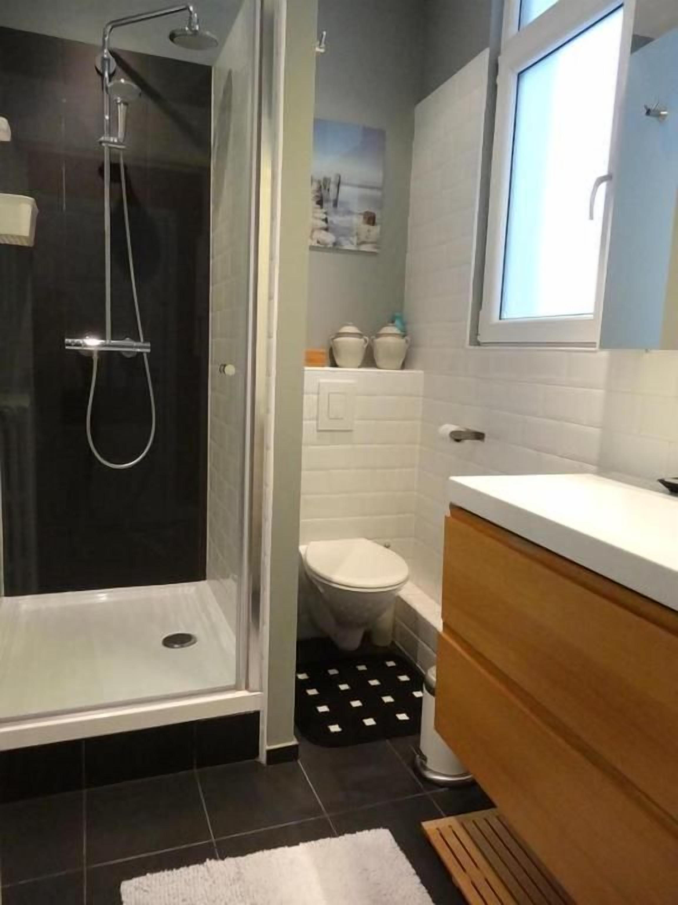 A bathroom with a glass-enclosed shower, a white toilet, and a wooden vanity.