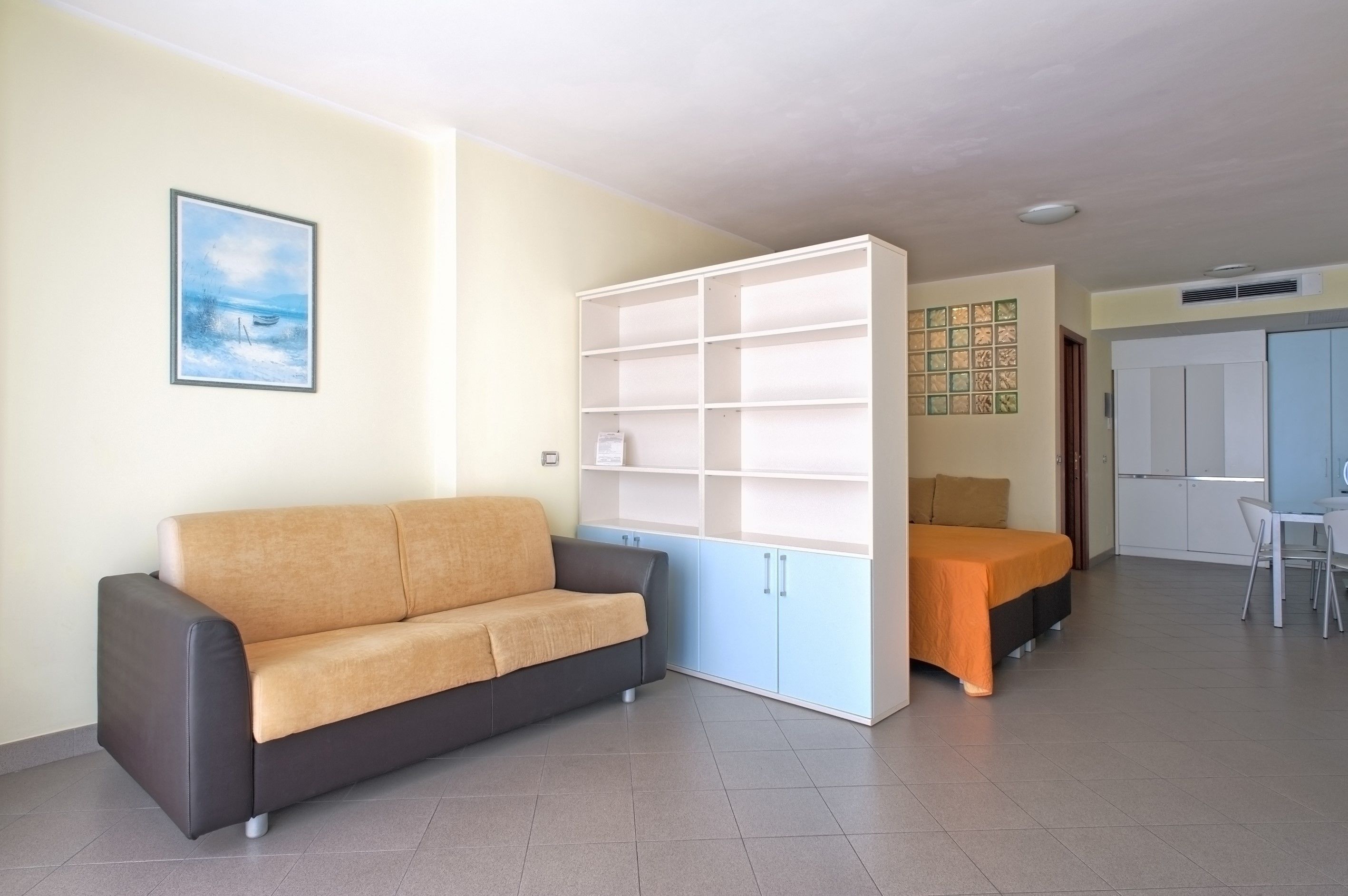 Ein modernes Wohnzimmer mit Sofa, Bett, Essbereich und Küche.