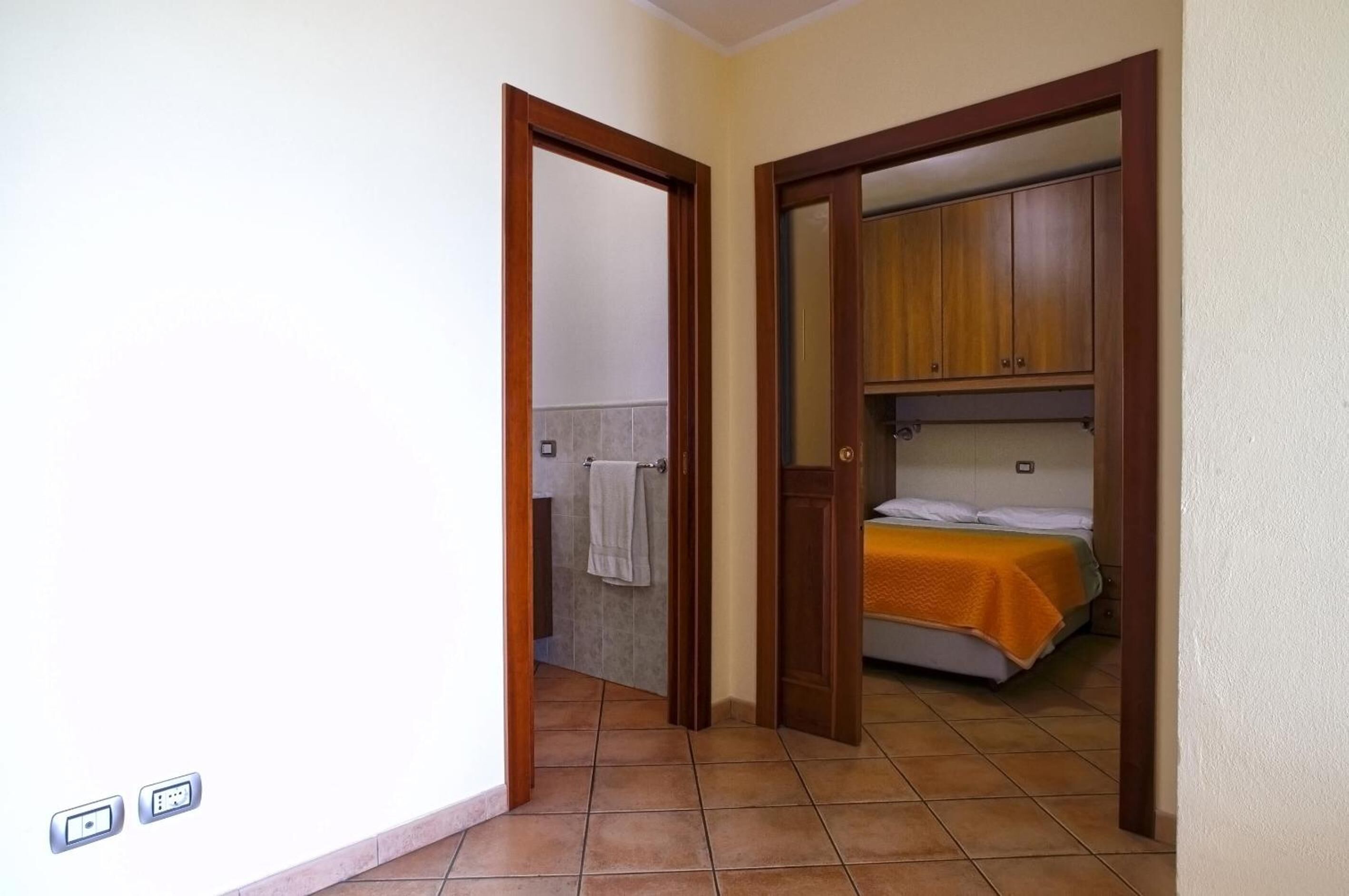 Una habitación con una cama, armarios de madera y un baño con una toalla colgada en la pared.