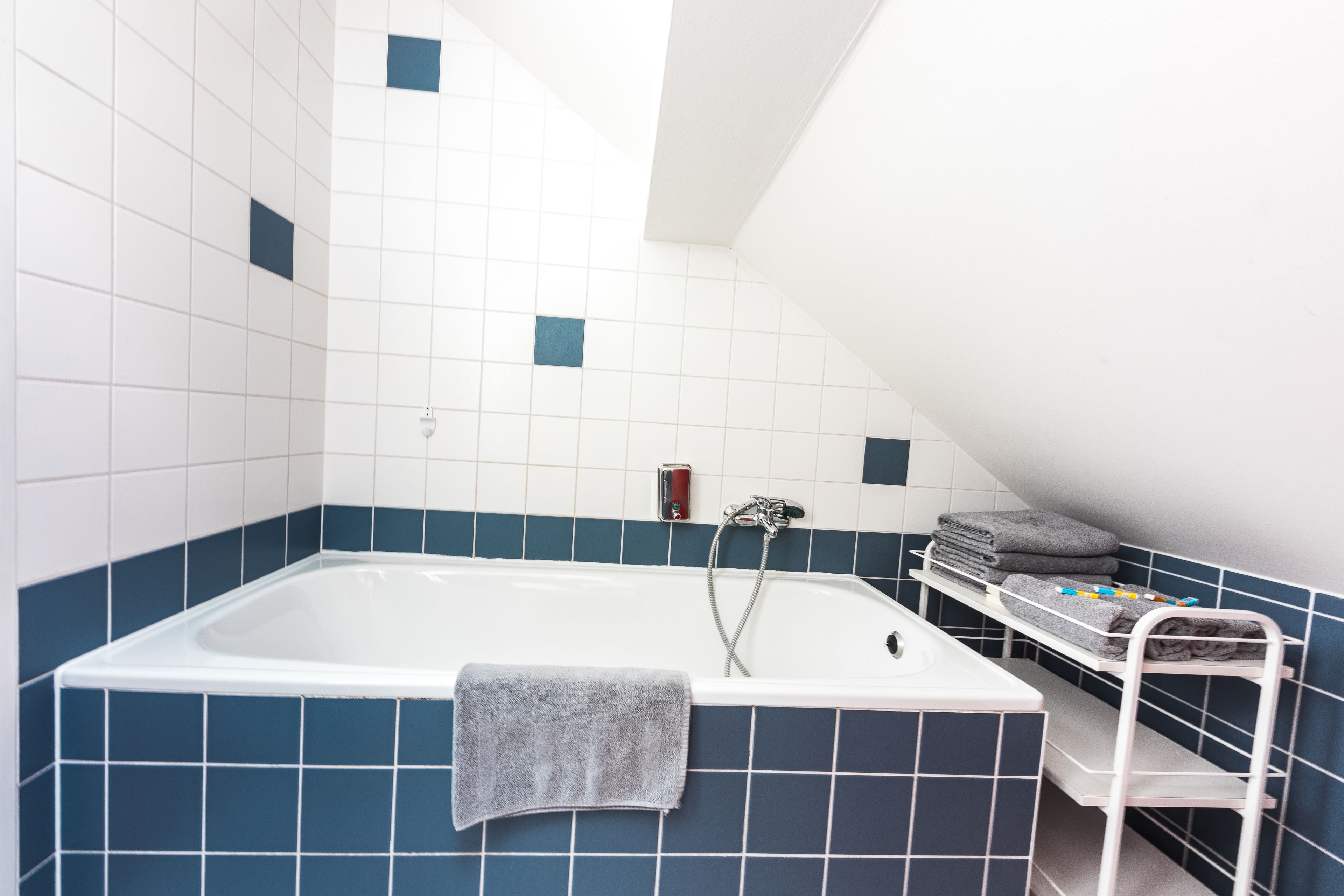 Ein Badezimmer mit einer Badewanne, einem Handtuchhalter und einem Regal mit Handtüchern.