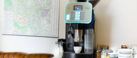 Una máquina de café con pantalla digital, una jarra de leche y una taza de café sobre una encimera.
