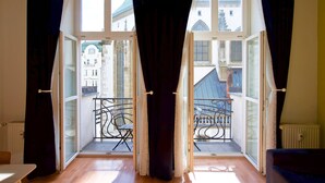A room with a large window, a view of a balcony with chairs, and a radiator on the wall. - Hotel and Apartments Jacob (Brno)