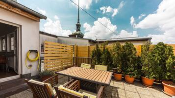 Relax in this serene outdoor patio surrounded by lush greenery and a charming wooden fence.