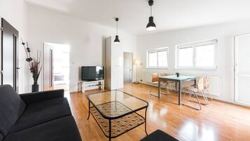 A modern living room with a glass coffee table, a sofa, and a dining area with a table and chairs.