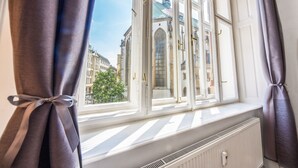 A room with a large window, white radiator, and curtains tied back. - Hotel and Apartments Jacob (Brno)