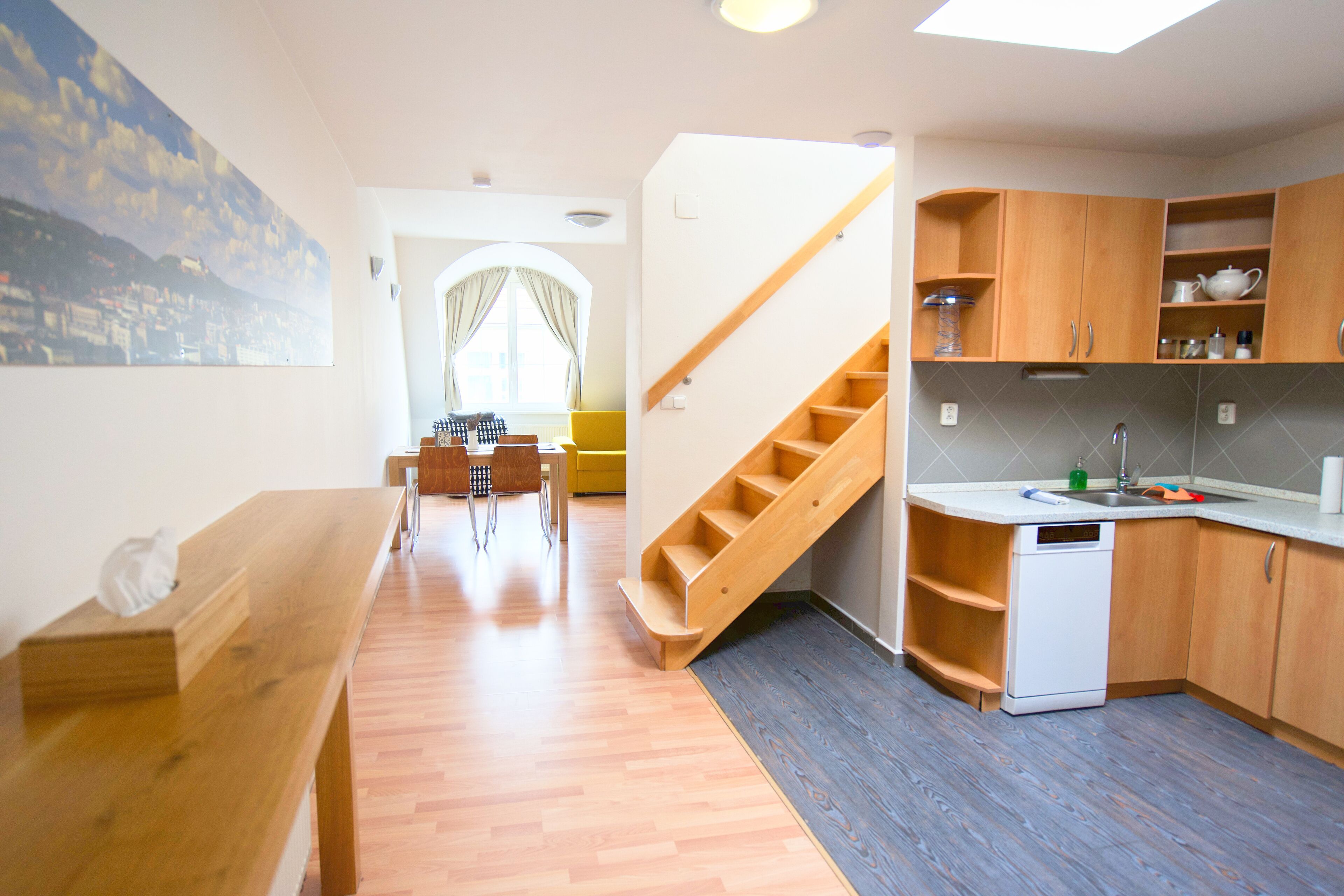 Una cocina moderna con armarios de madera, lavavajillas integrado y una zona de comedor con banco y sillas.