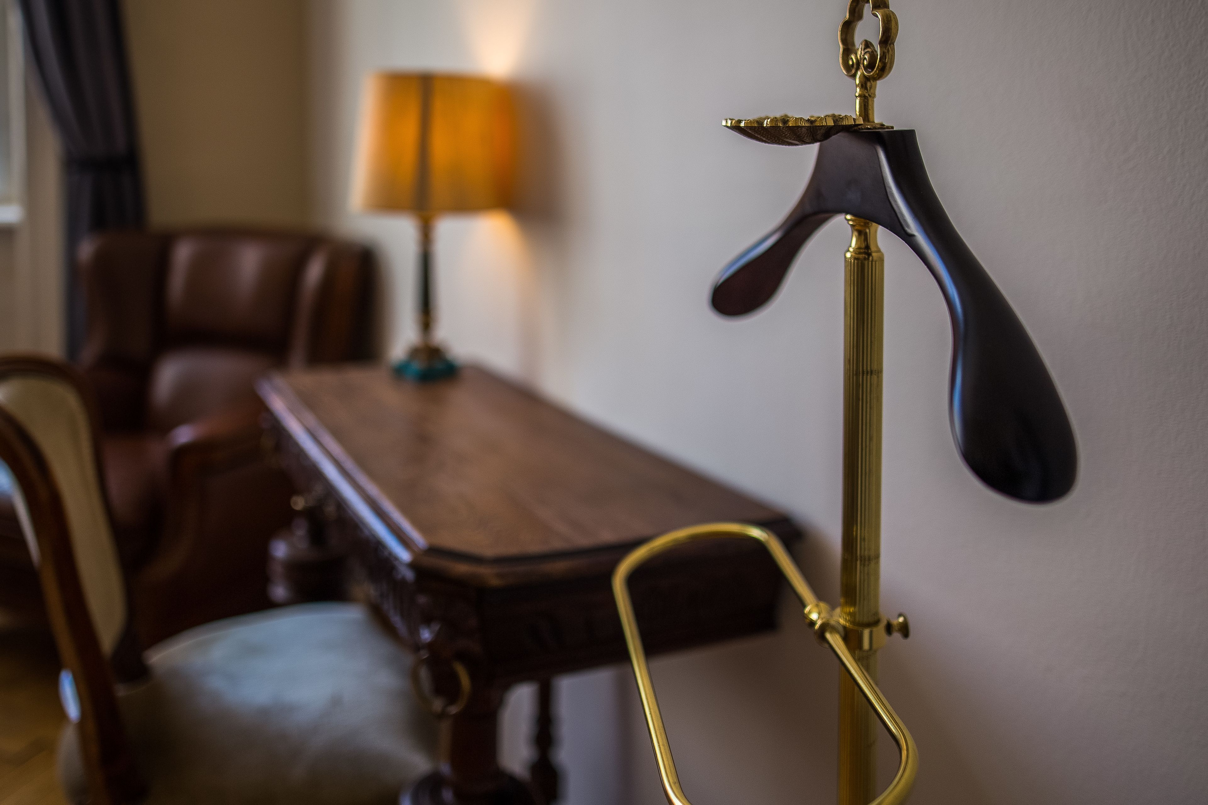 Una habitación con una mesa de madera, una silla de cuero y una lámpara de latón.