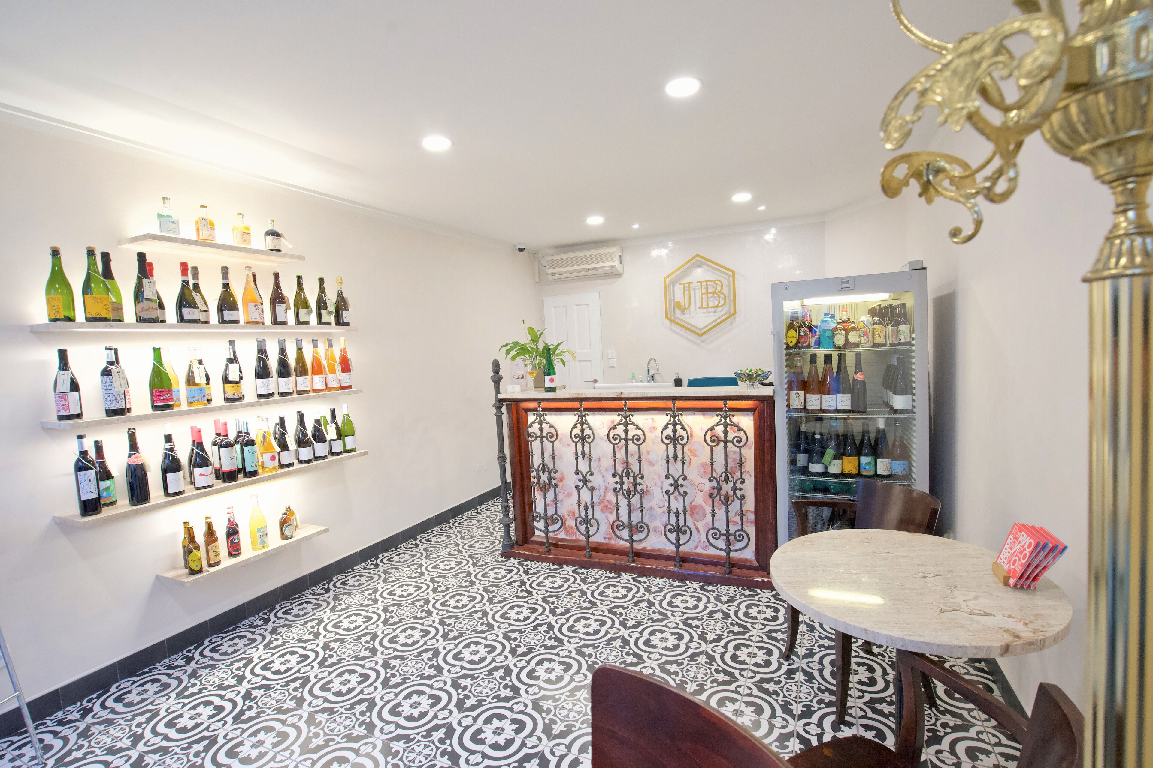 Uma área de bar com prateleiras de garrafas, uma mesa redonda e um pilar decorativo.