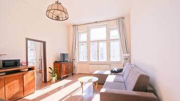 A living room with a sofa, a coffee table, a TV, a cabinet, and a plant.
