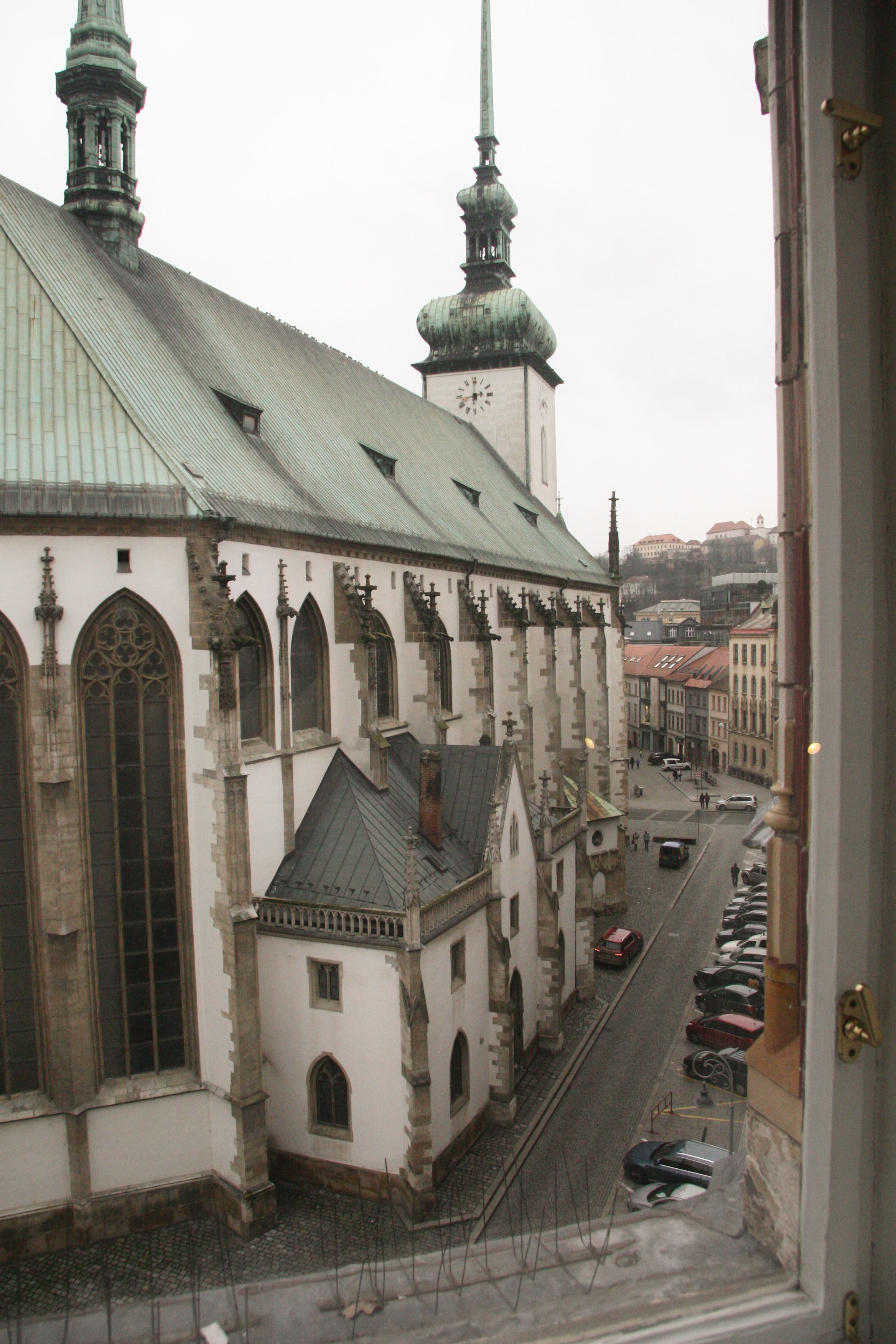 Une vue d’une église dotée d’un clocher et d’une rue où sont garées des voitures.