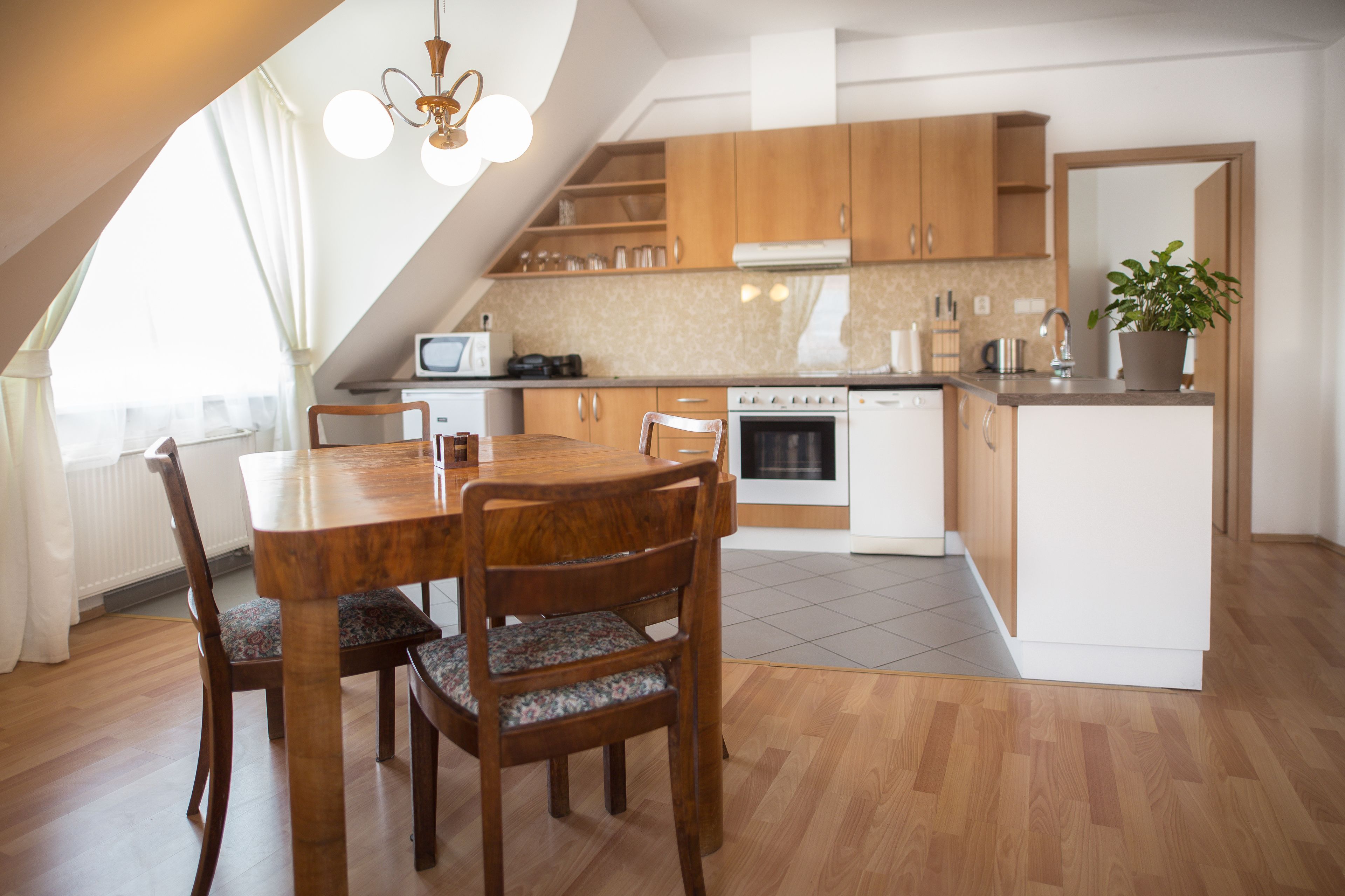 A modern kitchen with wooden cabinets, a dining table with chairs, and a built-in oven.