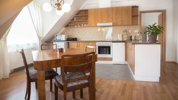 A modern kitchen with wooden cabinets, a dining table with chairs, and a built-in oven.