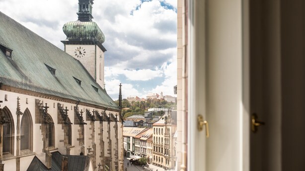 A view of a historic building with a clock tower and a church with pointed arches. - Hotel and Apartments Jacob (Brno)