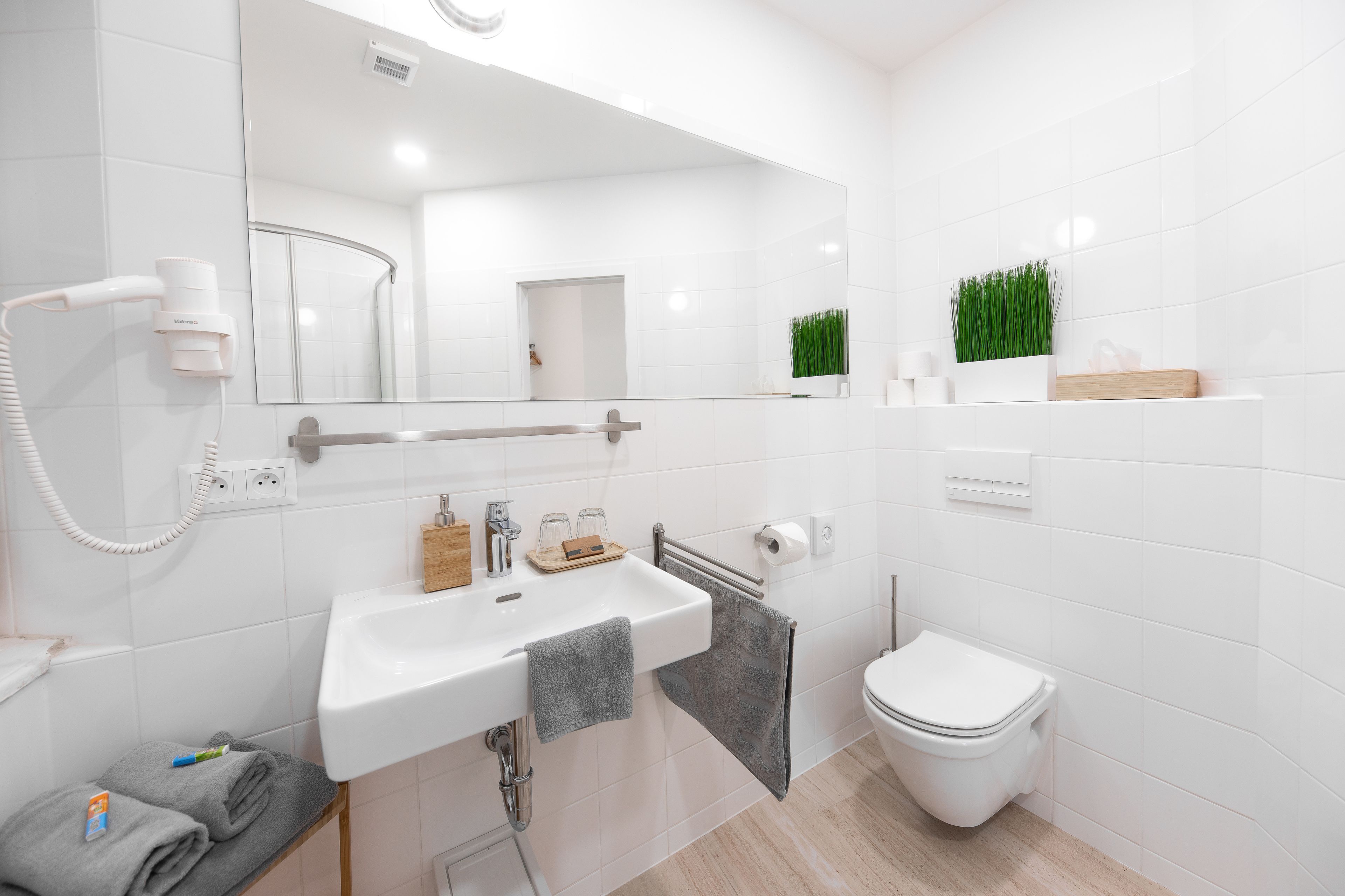 Une salle de bain moderne avec un lavabo blanc, un miroir et des toilettes.